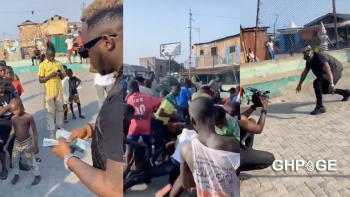 Medikal sprays money on the street for kids during a video shoot