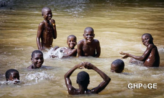 children happily swimming in dam